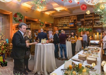 people attending a festive celebration in an elegant room with white linen dressed tables and a large table with food laid out